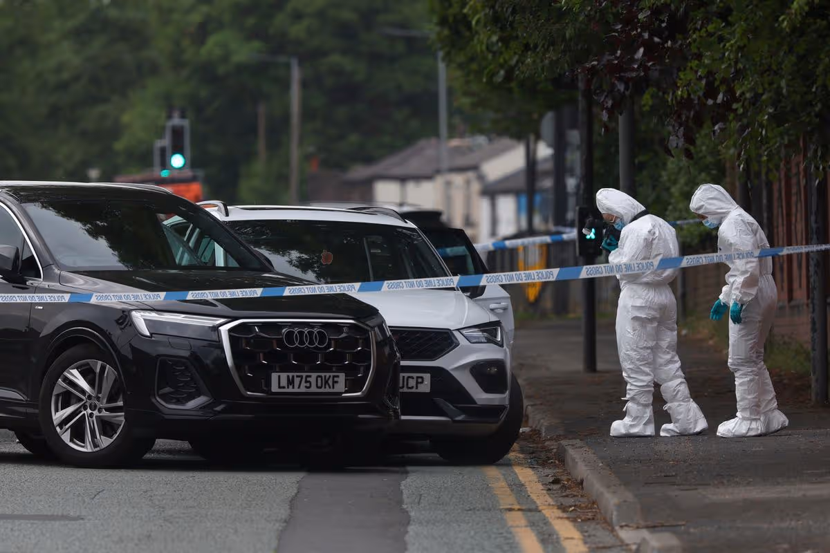 MANCHESTER, ENGLAND - MAY 22: Forensic officers attend the scene as a white car is boxed in by other unmarked cars behind a police cordon on the Bury New Road on May 22, 2026 in Manchester, England. It has been reported armed police have swarmed an area of Bury New Road in Whitefield following an incident. (Photo by Ryan Jenkinson/Getty Images)