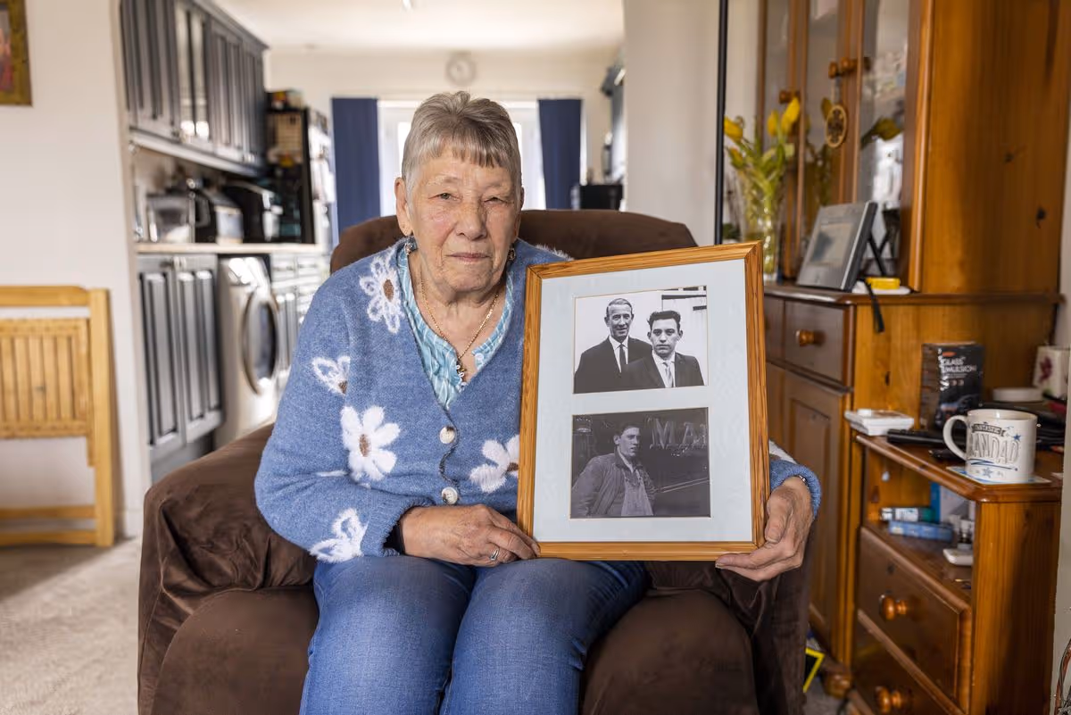 Nancy Barkley sitting an armchair holding up a picture of her brother, Great Train Robbery victim David Whitby