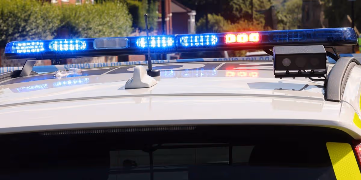An image depicting a police car, equipped with illuminated blue and red lights on its roof, suggesting active emergency response.
