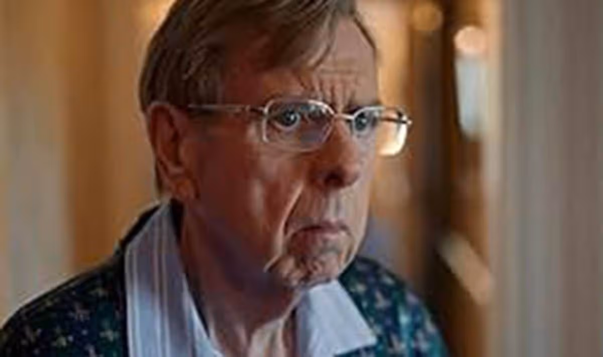 An elderly man with glasses looks afraid