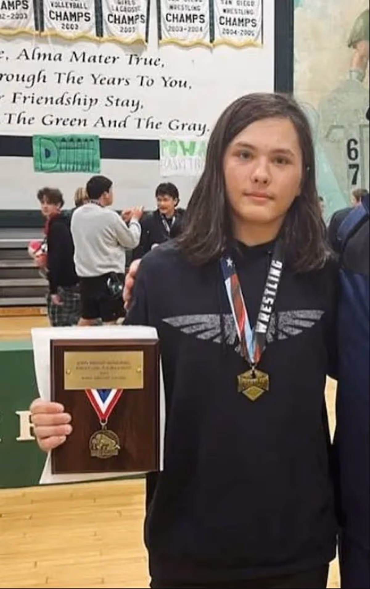 Cain Clark holding a medal in school