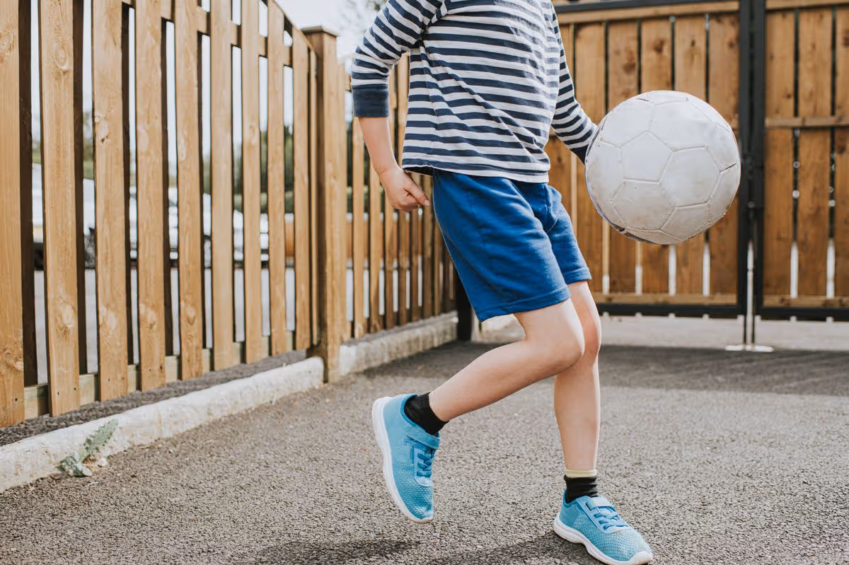 Boy playing football during lockdown in a back yard.