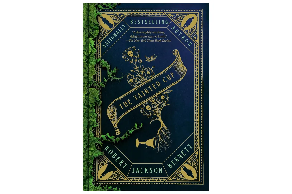 The Tainted Cup book cover by Robert Jackson Bennett, with gold illustrations of flowers, skulls, and a chalice on a dark blue background, framed by green vines.