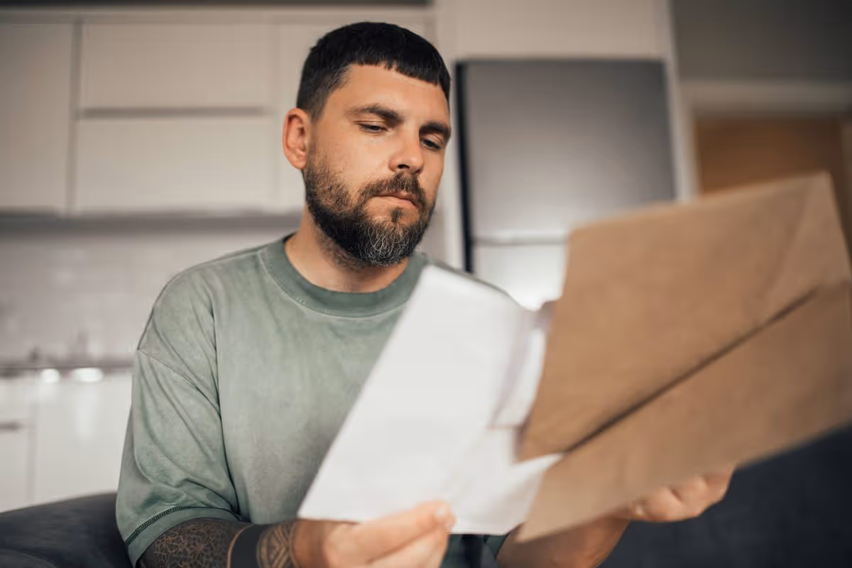Young entrepreneur analysing paper data, invoices, bills, credit payments or bank statement. Paperwork at home or freelance job. Problem with payments.