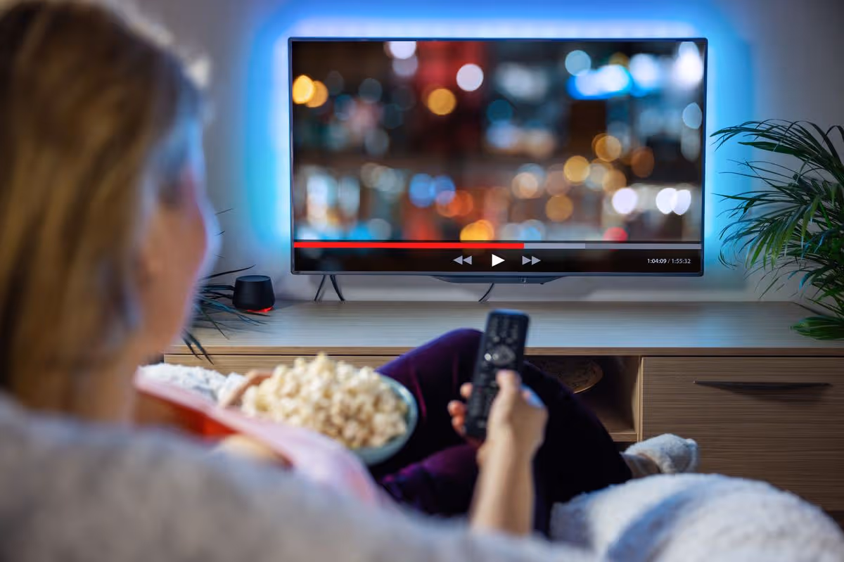 Female relaxing at home in evening and watching TV