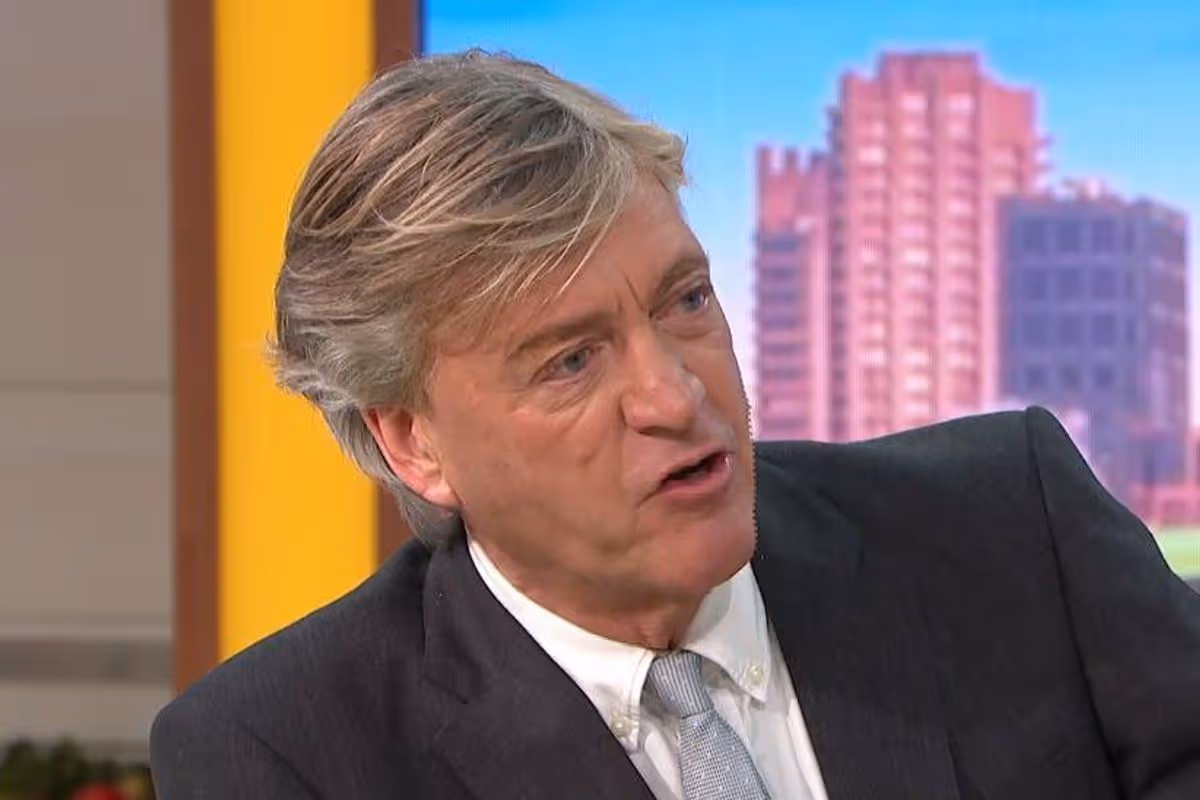 Richard Madeley in formal attire, consisting of a dark suit and a light-colored tie, appears to be engaged in a conversation, on GMB 
