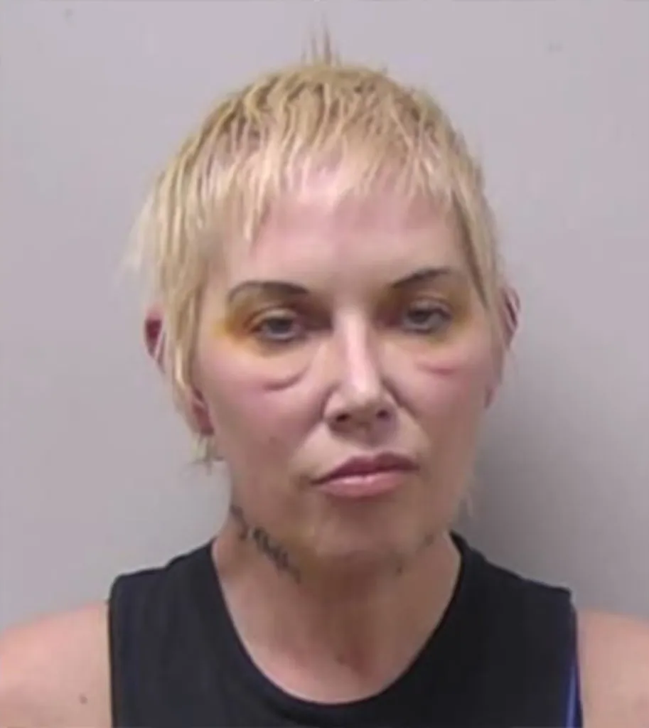 Mugshot of Kimberly Mathers, with short blonde hair and bruises around her eyes, wearing a black top.