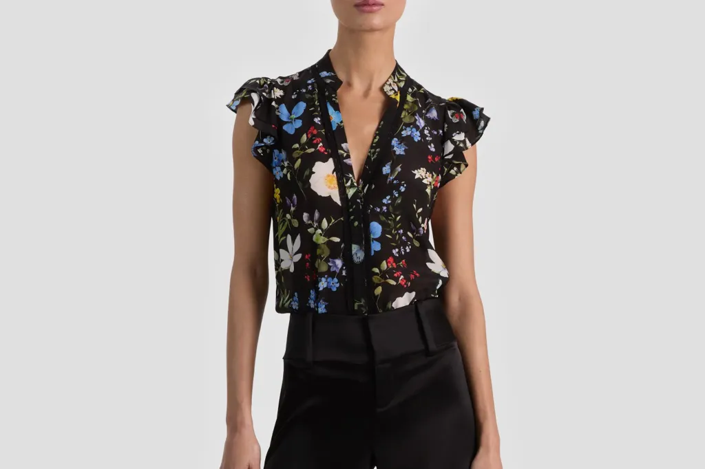 A person wearing a black floral blouse with short ruffled sleeves and black pants.