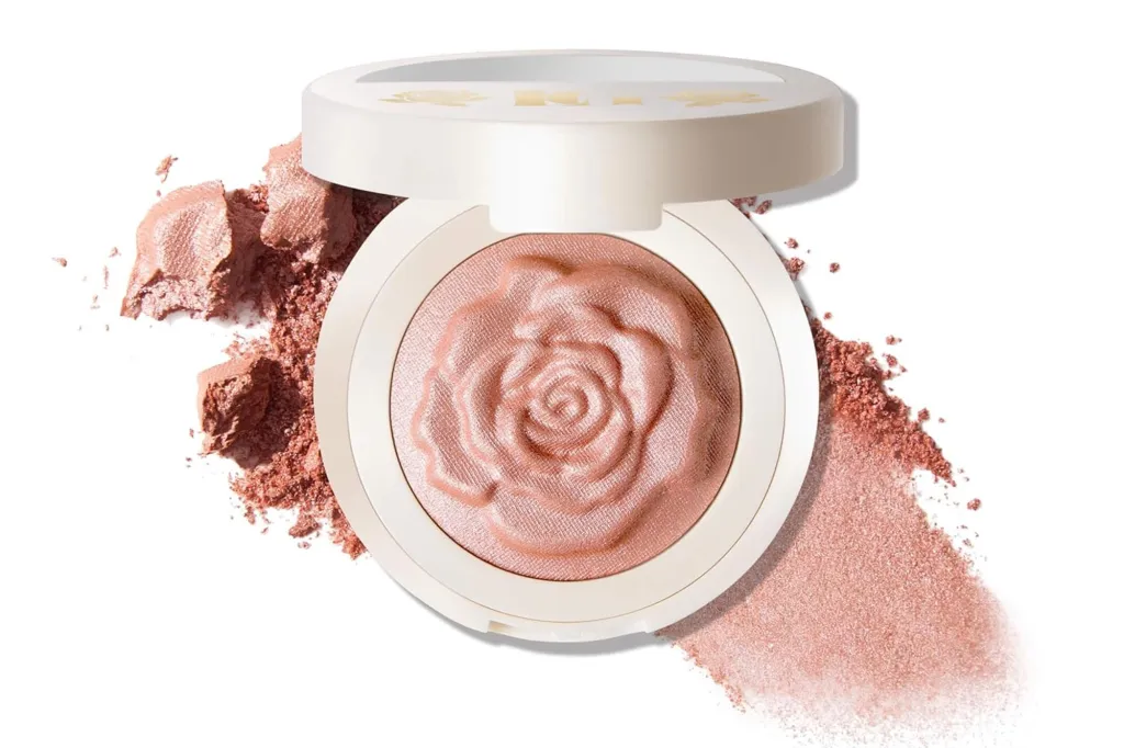 Pink rose-shaped blush in a white compact with blush powder spilled around it.