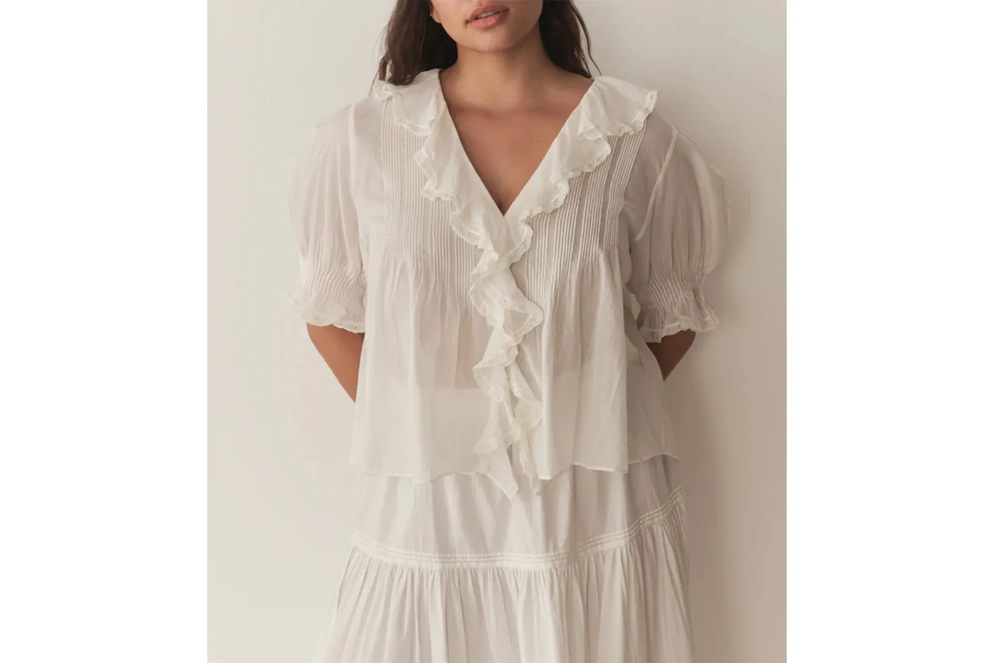 Woman wearing a white Henri top with ruffles and a matching skirt.