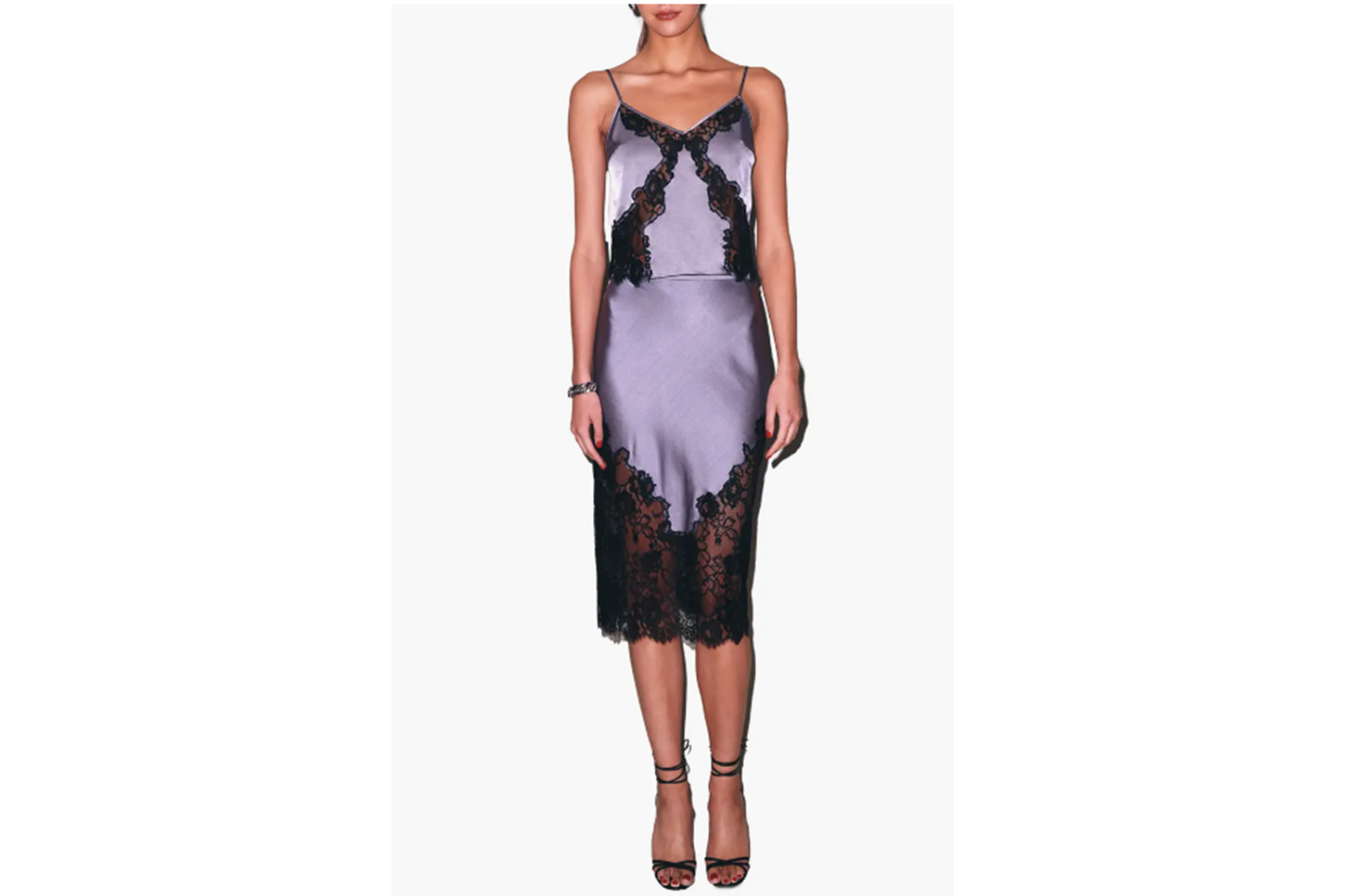 A woman models a purple silk slip dress with black lace trim.