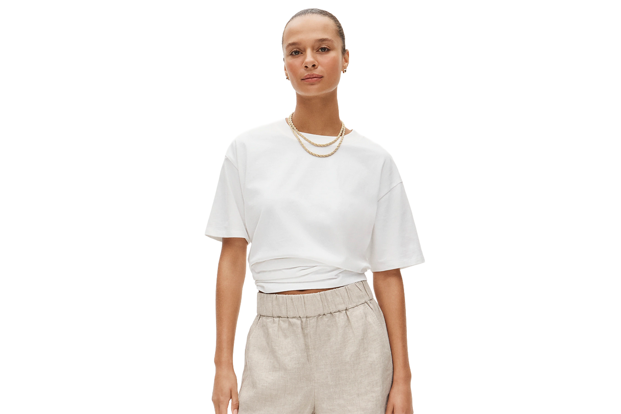 A woman wearing a white t-shirt and beige shorts.