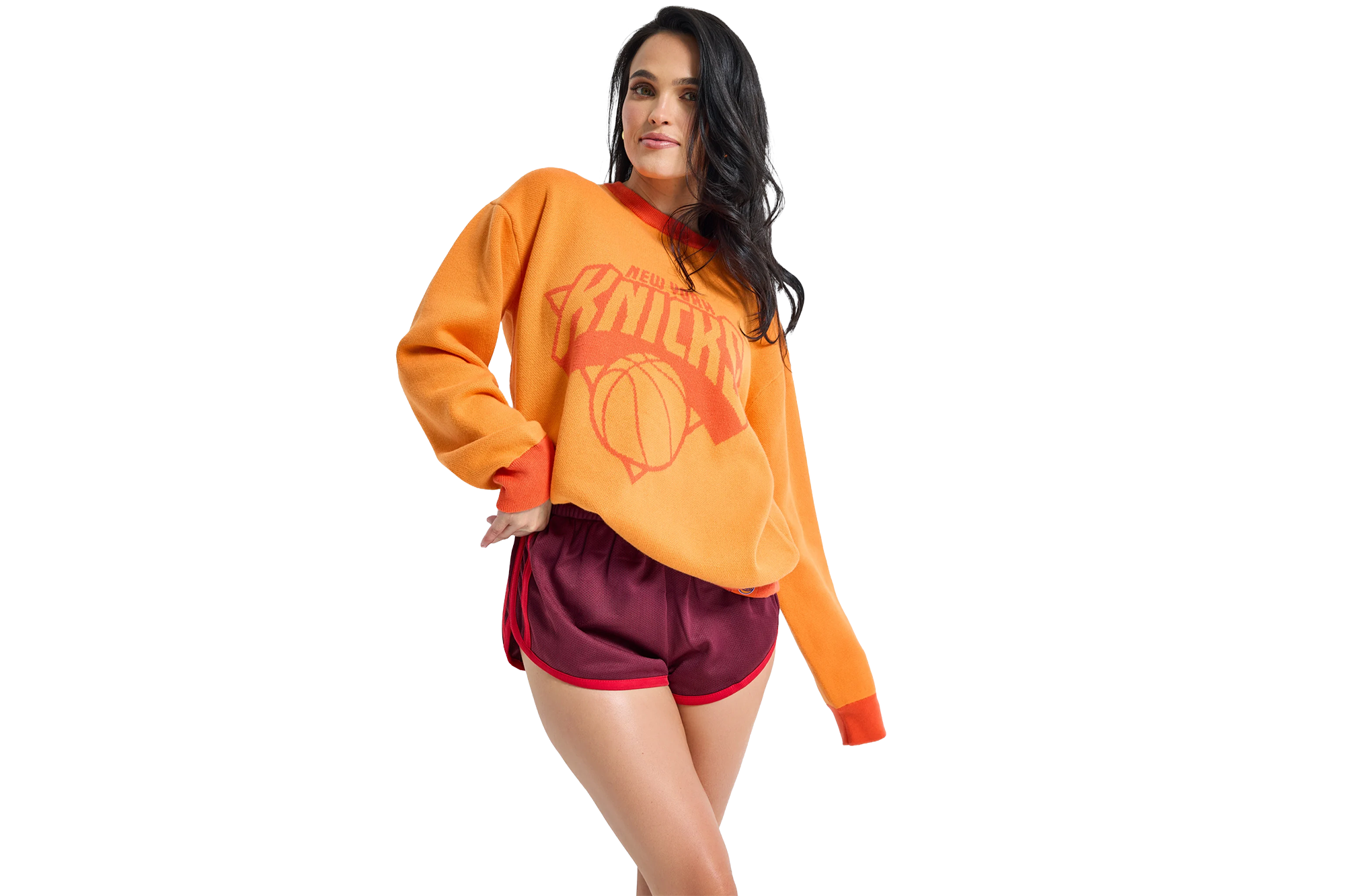 A woman in an orange New York Knicks sweatshirt and maroon shorts.