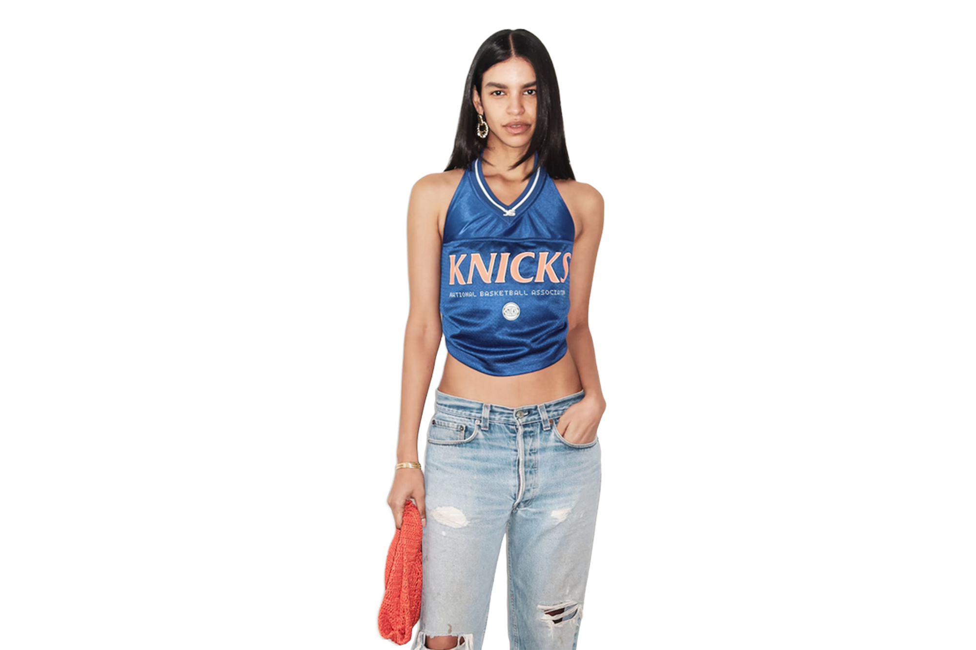 A woman models a blue halter top with "KNICKS" written in orange, ripped jeans, and an orange knit towel.