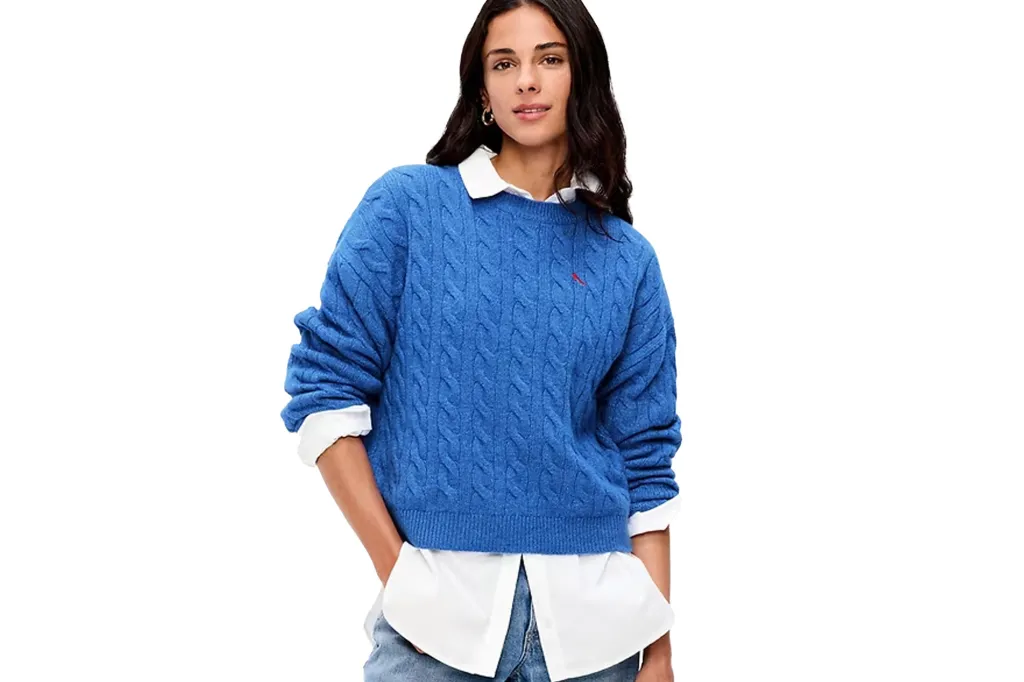 Woman in a blue cable knit sweater and white shirt.