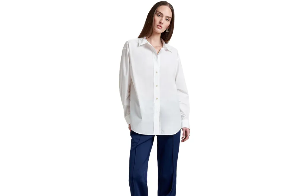 A woman wears a long-sleeved white button-down shirt and blue pants.