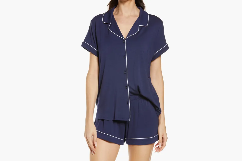 A model wears navy blue short pajamas with white piping.