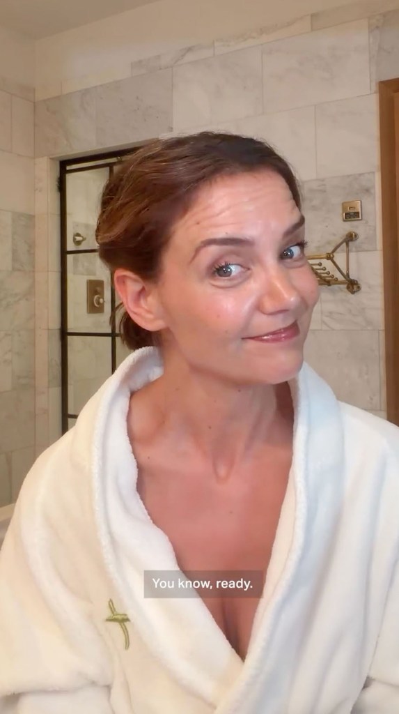 Katie Holmes in a white robe, ready for a beauty routine.