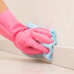 0_Young-adult-woman-hand-in-pink-rubber-protective-glove-using-blue-dry-rag-and-wiping-light-wooden.jpeg