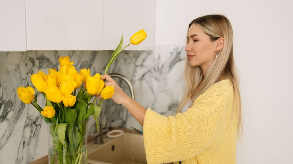 1775966786_0_A-beautiful-woman-with-long-hair-in-a-yellow-cardigan-is-pruning-flowers-at-home-changing-the-wate.jpeg