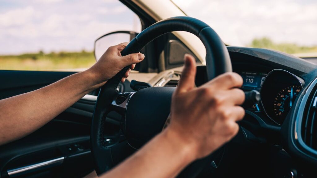 1776310305_0_Close-Up-of-Hands-Holding-a-Steering-Wheel-Inside-a-Car-on-a-Sunny-Day.jpg