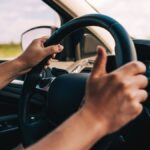 1776310305_0_Close-Up-of-Hands-Holding-a-Steering-Wheel-Inside-a-Car-on-a-Sunny-Day.jpg